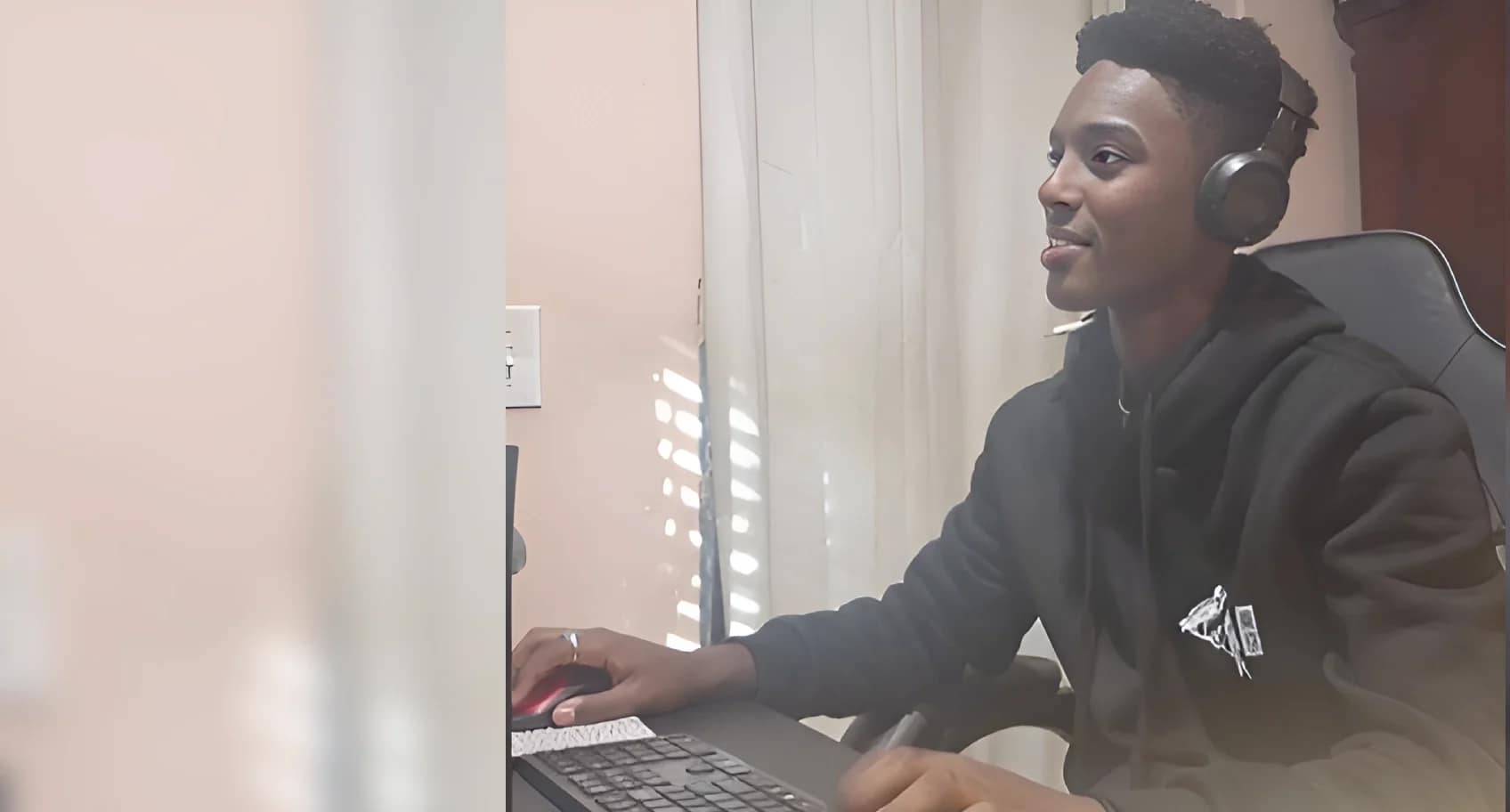 A young man working on a laptop at a desk indoors.
