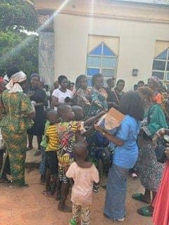 A group of people gathered outside a building, many holding books or papers.