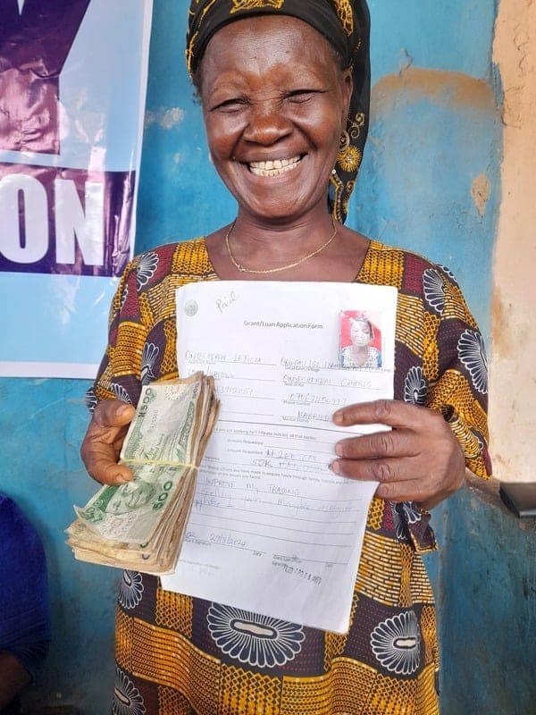 A smiling woman holds a document and money.